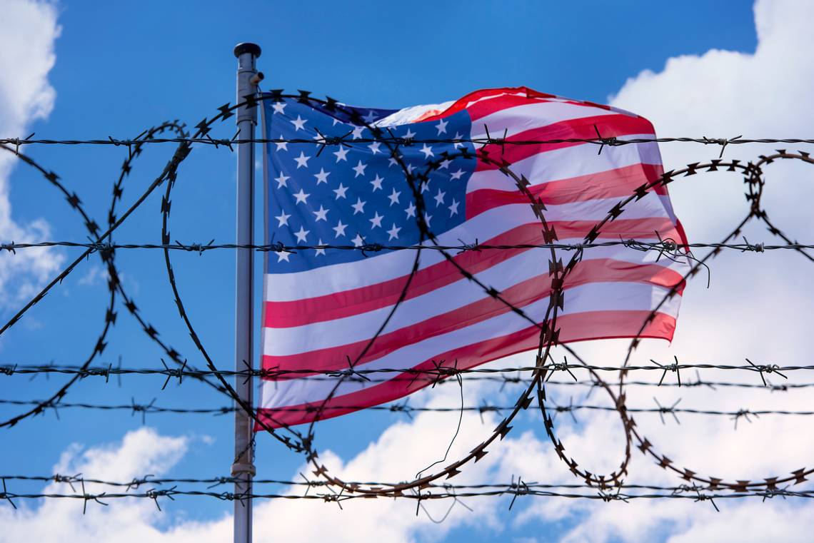 US Flag behind barb wire fence